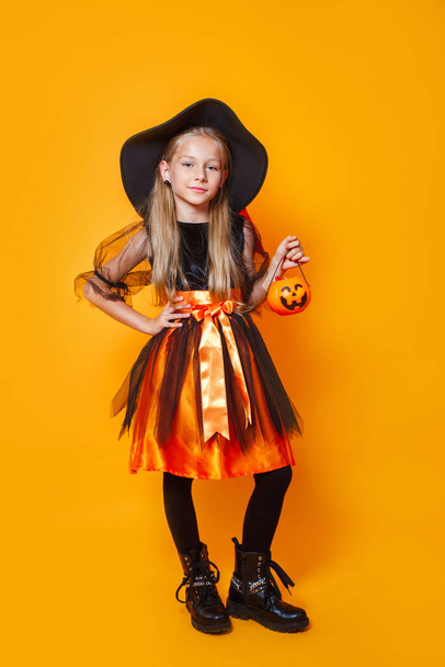 Little girl dressed as a witch and holding a pumpkin basket - Fotoğraf, Görsel
