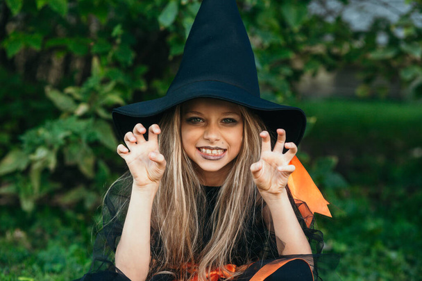 Little girl in witch costume having fun on Halloween trick or treat - Photo, image