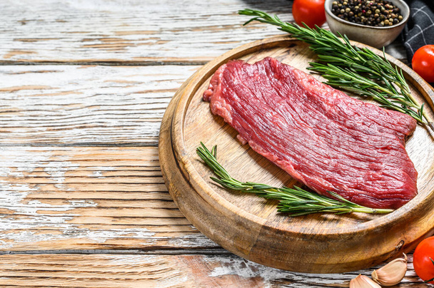 Raw Flank steak on a cutting board. Fresh Marble beef meat black Angus. White wooden background. Top view. Copy space. - Photo, Image