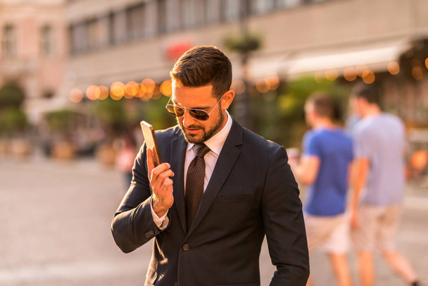 A businessman walking and talking on his phone - Фото, изображение