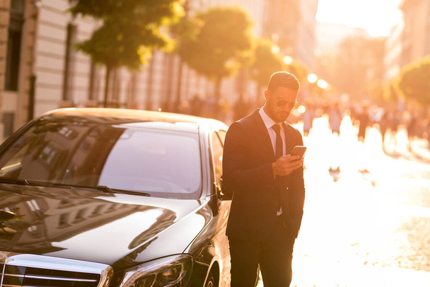 A businessman walking and using his smartphone - Zdjęcie, obraz