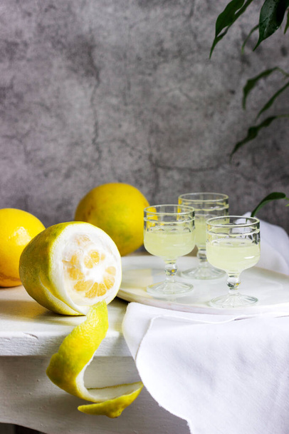 Italienischer Likör Limoncello in Kristallgläsern und reifen Zitronen auf einem Holztisch. - Foto, Bild