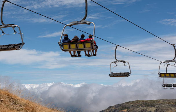 Ihmiset ratsastavat hiihtoaseman hisseillä, katselevat vuoria ja horisonttia, takana - Valokuva, kuva