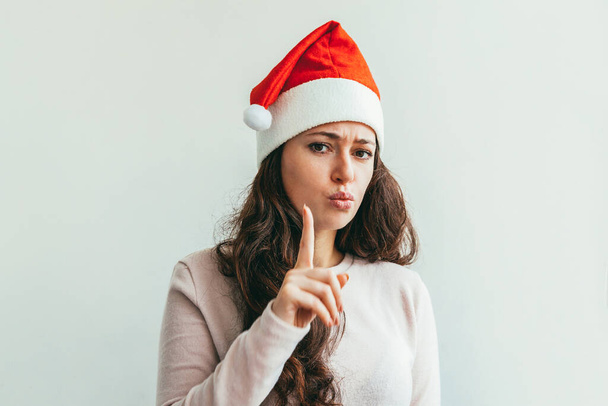赤いサンタクロースの帽子で長い髪を持つ美しい女の子は、白の背景に幸せと興奮を探して隔離されました。若い女性の肖像画、真の感情。幸せなクリスマスと新年の休日 - 写真・画像