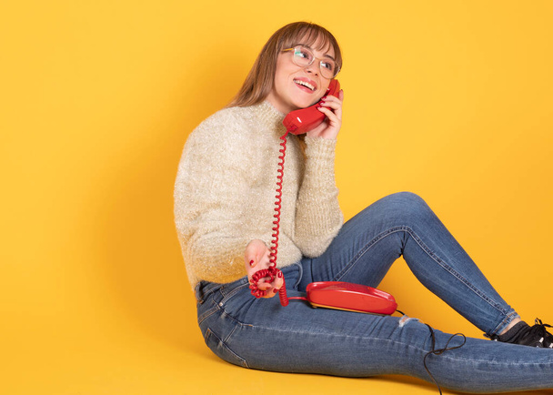 mujer hablando en viejo teléfono amarillo fondo - Foto, Imagen