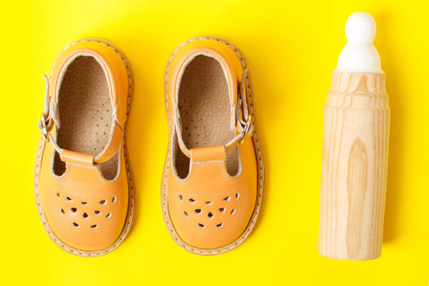 детские сандалии и деревянная эко-игрушка, первая обувь и игрушка малыша - Фото, изображение