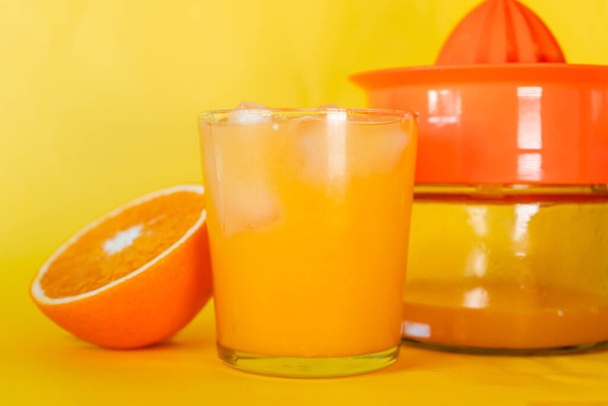 Ποτήρι με υπέροχο βιολογικό χυμό πορτοκαλιού με Half Orange και σφιγκτήρα πίσω.  - Φωτογραφία, εικόνα