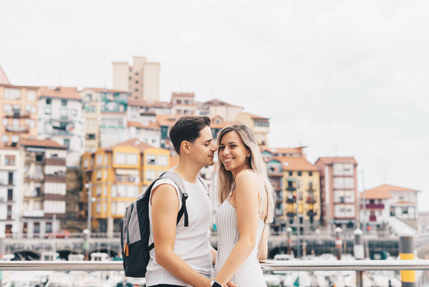 Mladý pár s přístavem a malou vesničkou Bermeo za nimi ve Vizcaya, Španělsko - Fotografie, Obrázek