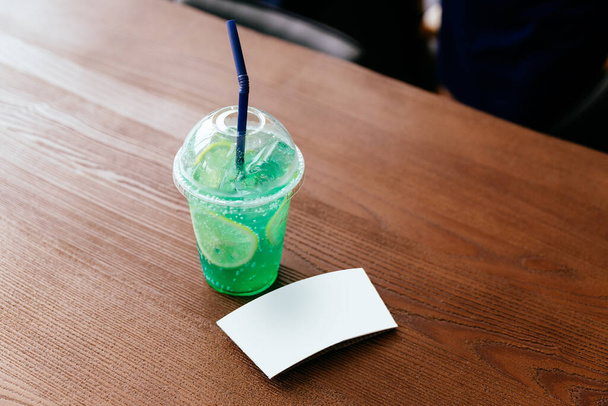 Tahta bir masada dilimlenmiş limonlu yeşil buzlu soda kabı. Kol kolu şablonu. - Fotoğraf, Görsel