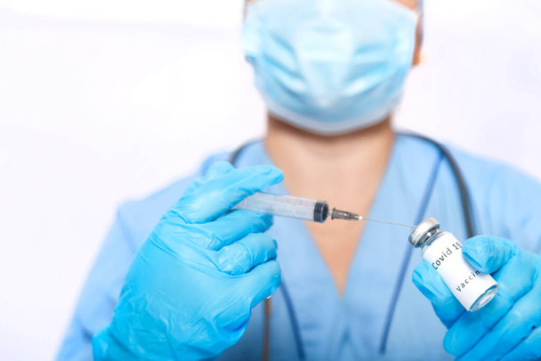 A gloved doctor fills a syringe with a coronavirus vaccine. - 写真・画像