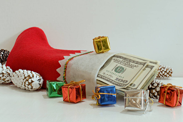 pack of dollars as a gift in christmas boot on blurred white background - Фото, изображение
