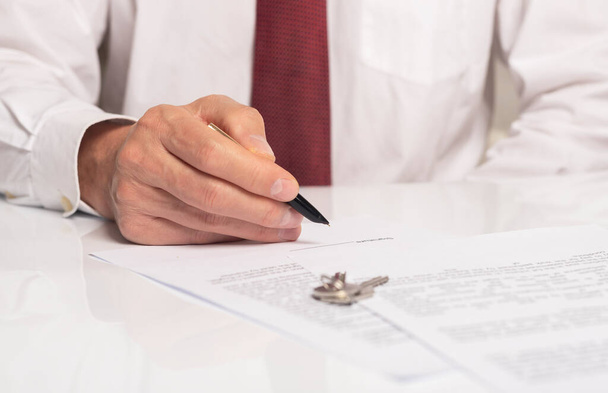 Businessman signing contract with keys on table. real estate agreement concept. - Foto, imagen