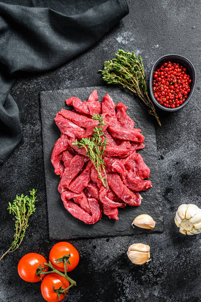 Raw beef Stroganoff meat. Black background. Top view. - Foto, afbeelding