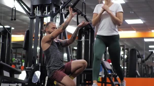 Gym les met een jonge grappige trainer man een aspirant jonge vrouw lunges - Video