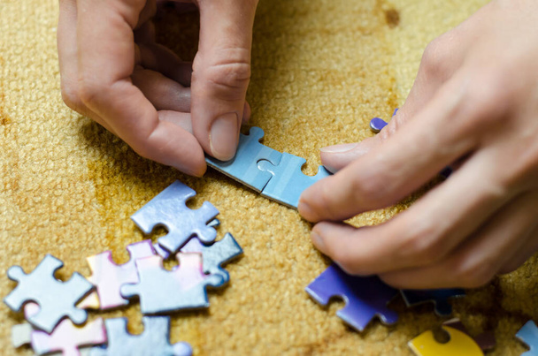 女性の手がパズルを集める。女性はカラフルなモザイクを折る - 写真・画像
