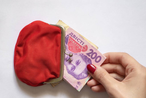 200 UAH in a red wallet and a woman's hand on an isolated background, Ukrainian money - Fotó, kép