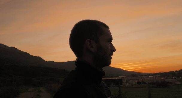 Silhouette eines jungen Mannes mit einem Sonnenuntergang im Hintergrund - Foto, Bild