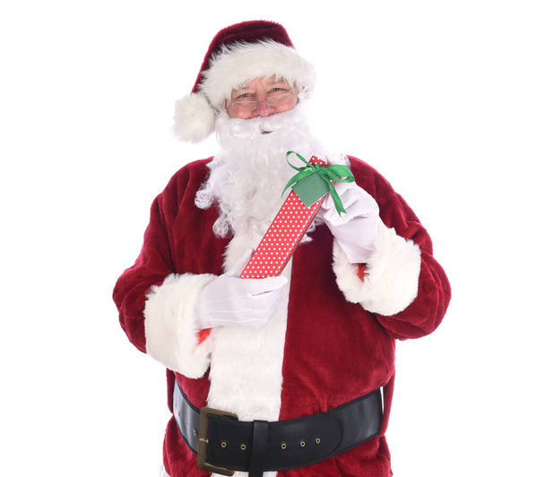 Santa holidng a polka dot paper wrapped Christmas Present, isolated on white. - 写真・画像