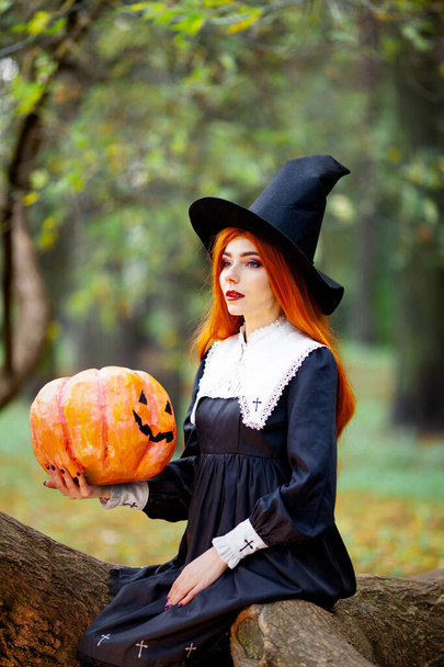 roodharig meisje in het beeld van een heks in een halloween kostuum - Foto, afbeelding
