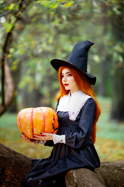 chica pelirroja en la imagen de una bruja en un disfraz de halloween - Foto, Imagen