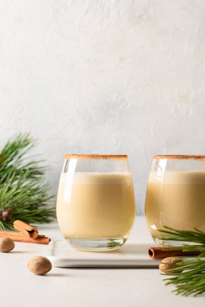 Two holiday Christmas eggnog with grated cinnamon and nutmeg on white. Close up. Vertical format. - Фото, зображення