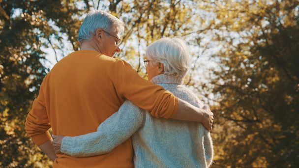 Um velho casal feliz a abraçar-se no parque. Um idoso a namoriscar com uma idosa. Romance na velhice no dia de outono - Foto, Imagem