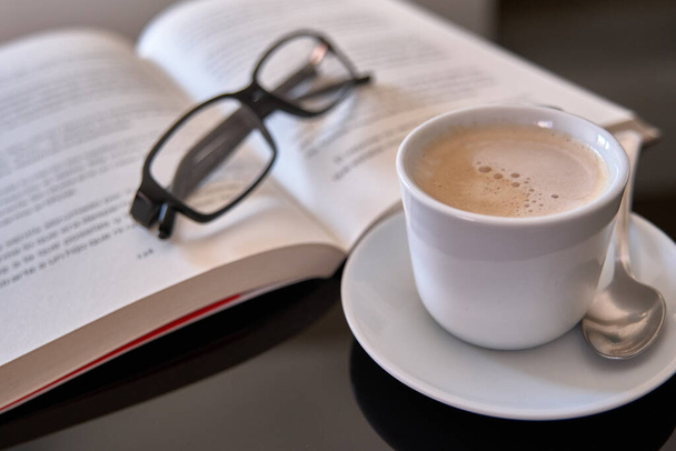 Van egy csésze kávé olvasás egy könyvet szemüveg - Fotó, kép