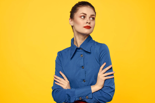 Retrato de una mujer en una camisa azul con brillante maquillaje labios rojos fondo amarillo vista recortada - Foto, imagen