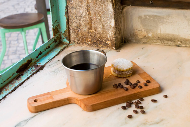 コーヒー豆を入れたカップの中のイタリアのブラックコーヒーと、砂糖と真岡鍋の後ろに手作りのクッキー。窓の近くのヴィンテージブラウンの背景のすべて。健康的な朝食. - 写真・画像