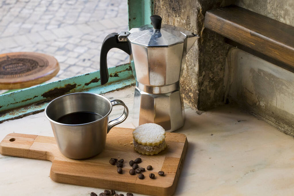 Café preto italiano em uma xícara com grãos de café e um biscoito artesanal com açúcar e um pote Moka atrás. Tudo no fundo marrom vintage perto da janela. Café da manhã saudável. - Foto, Imagem