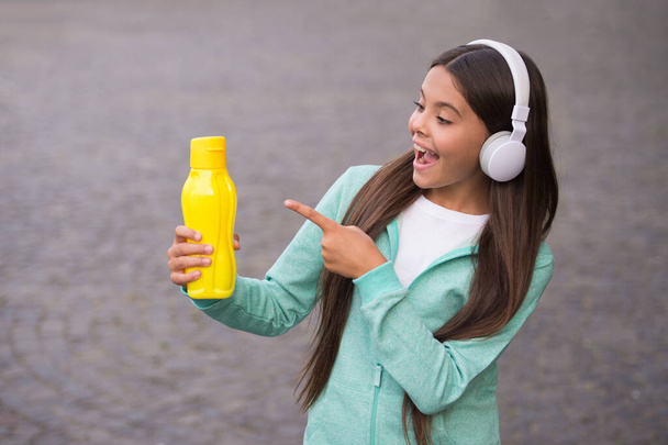 happy teenage girl pointing finger on water bottle going to drink, refreshment - 写真・画像