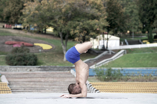 Athletic man doing yoga asanas in the park - Foto, afbeelding