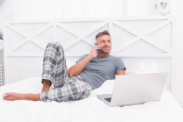 Education via Internet. domestic lifestyle with mobile abuse. handsome man online dating. relaxed male in bedroom. guy enjoying internet. social media addiction. laptop addict. work hard with no rest - Fotografie, Obrázek