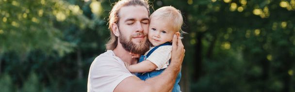 Proud father hugging embracing toddler baby boy. Young parent holding child son on arms. Authentic lifestyle tender moment. Single dad family life. Happy fatherhood. Web banner header. - Photo, Image
