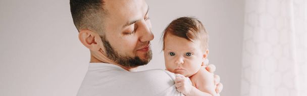 Ο μπαμπάς κουβαλάει νεογέννητο μωρό στον ώμο. Άντρας γονιός κρατά παιδί κόρη γιο στην αγκαλιά. Αυθεντικό οικογενειακό ντοκιμαντέρ. Γιορτές Πατέρων. Τίτλος banner ιστού. - Φωτογραφία, εικόνα