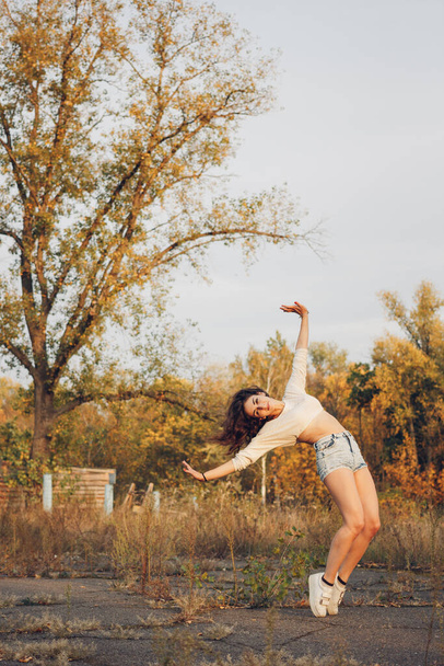 Beautiful brunette outdoors doing some acrobatic activity at sunset time. - Fotoğraf, Görsel