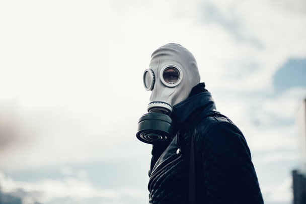 jeune homme occasionnel dans un masque à gaz debout dans la rue dans une ville vide - Photo, image