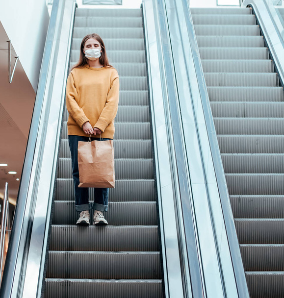 lone woman in a protective mask standing on the escalator steps - Foto, Bild