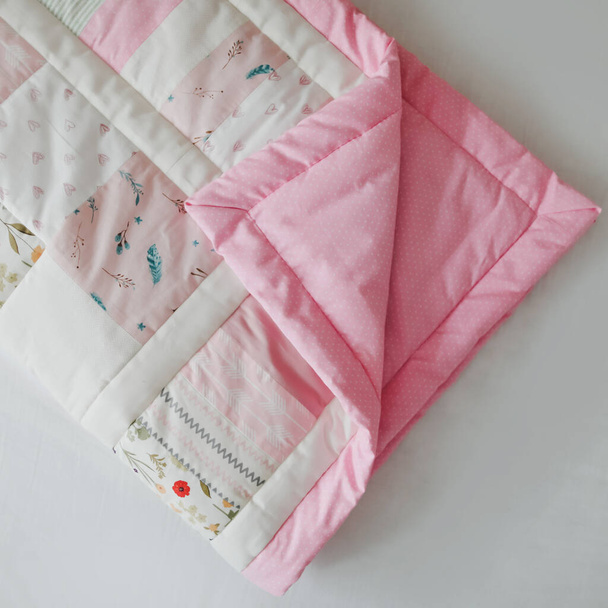 Pink patchwork blanket top view.  Cozy baby girl cot with blanket. Bedding and textile for children nursery. Nap and sleep time  - Foto, imagen