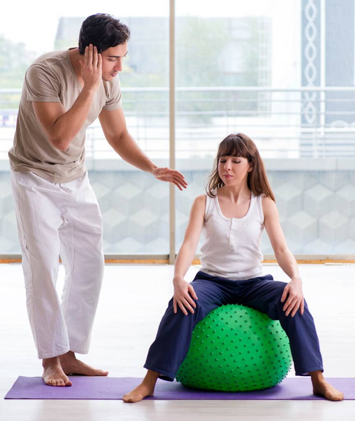 Entrenador personal ayudando a la mujer en el gimnasio con bola de estabilidad - Foto, Imagen