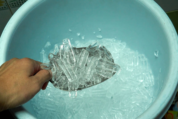 πάγος κύβος με μεταλλική σέσουλα στο χέρι - Φωτογραφία, εικόνα