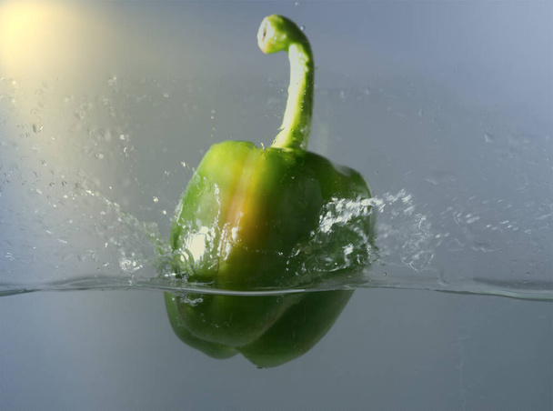 Vintage zöld paprika dobott a vízbe egy csepp vízzel. - Fotó, kép