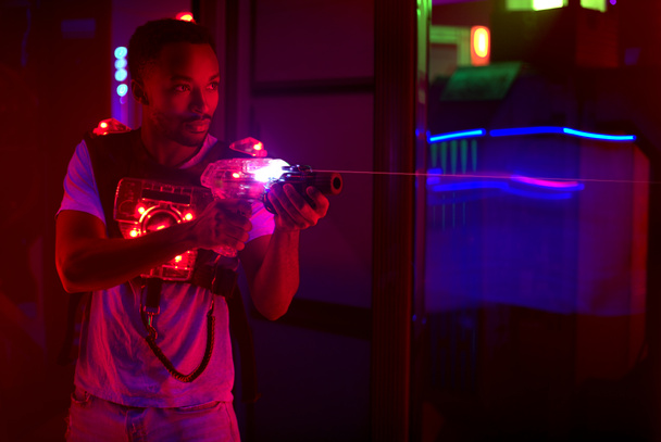 laser tag player holding gun in amusement center playing game - Photo, image