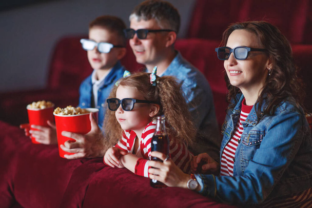 Family mom father and children are watching a projector, TV, cinema, movies with popcorn in the cinema. - Photo, Image