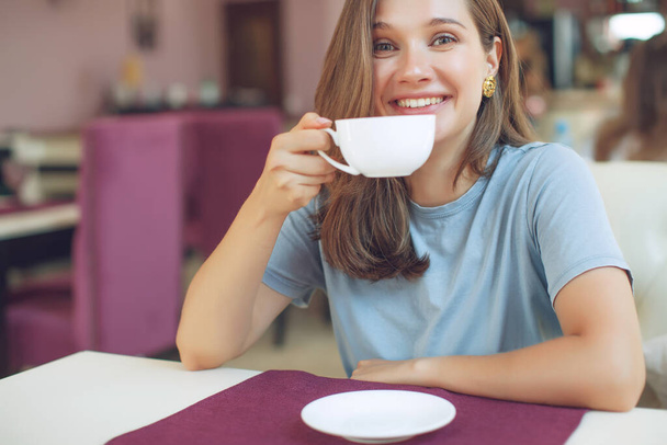 Figyelmes, érett nő ül egy kávézóban egy bögrével a kezében. Egy középkorú nő teát iszik gondolkodás közben. Pihentető és gondolkodó kávézás közben. - Fotó, kép