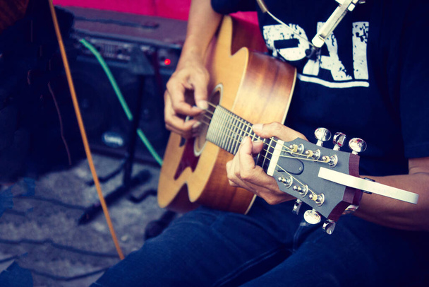 Κοντινά δάχτυλα του ανθρώπου που παίζει ακουστική κιθάρα σε ρετρό φίλτρο - Φωτογραφία, εικόνα