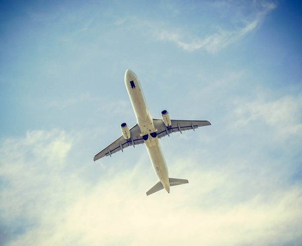 wit vliegtuig in blauwe lucht in retro filter - Foto, afbeelding