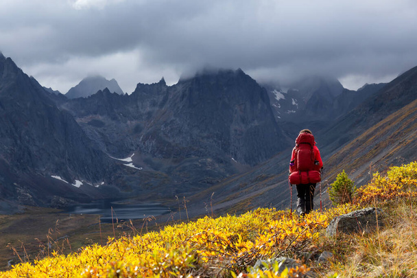 Mochilero mujer en sendero panorámico rodeado de montañas resistentes - Foto, imagen