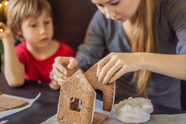 Young mother and kid making gingerbread house on Christmas eve - Fotoğraf, Görsel