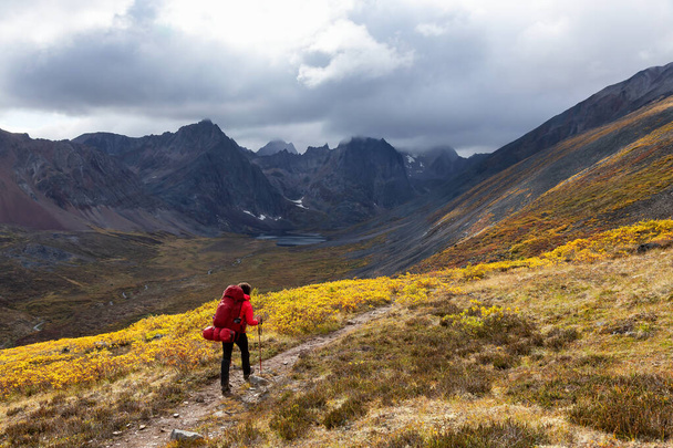 Mochilero mujer en sendero panorámico rodeado de montañas resistentes - Foto, imagen